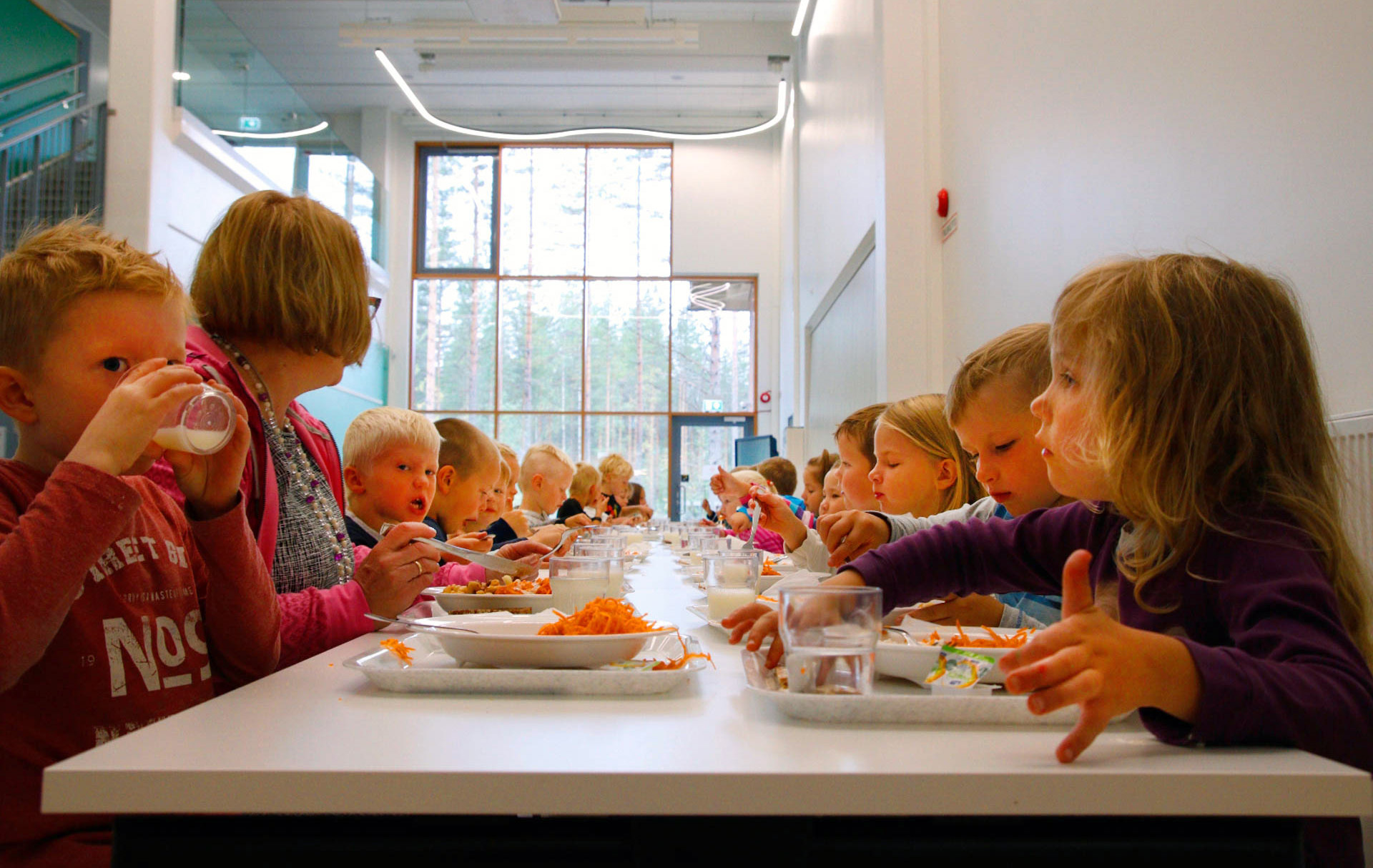 Lapset syövät koulun ruokalassa.