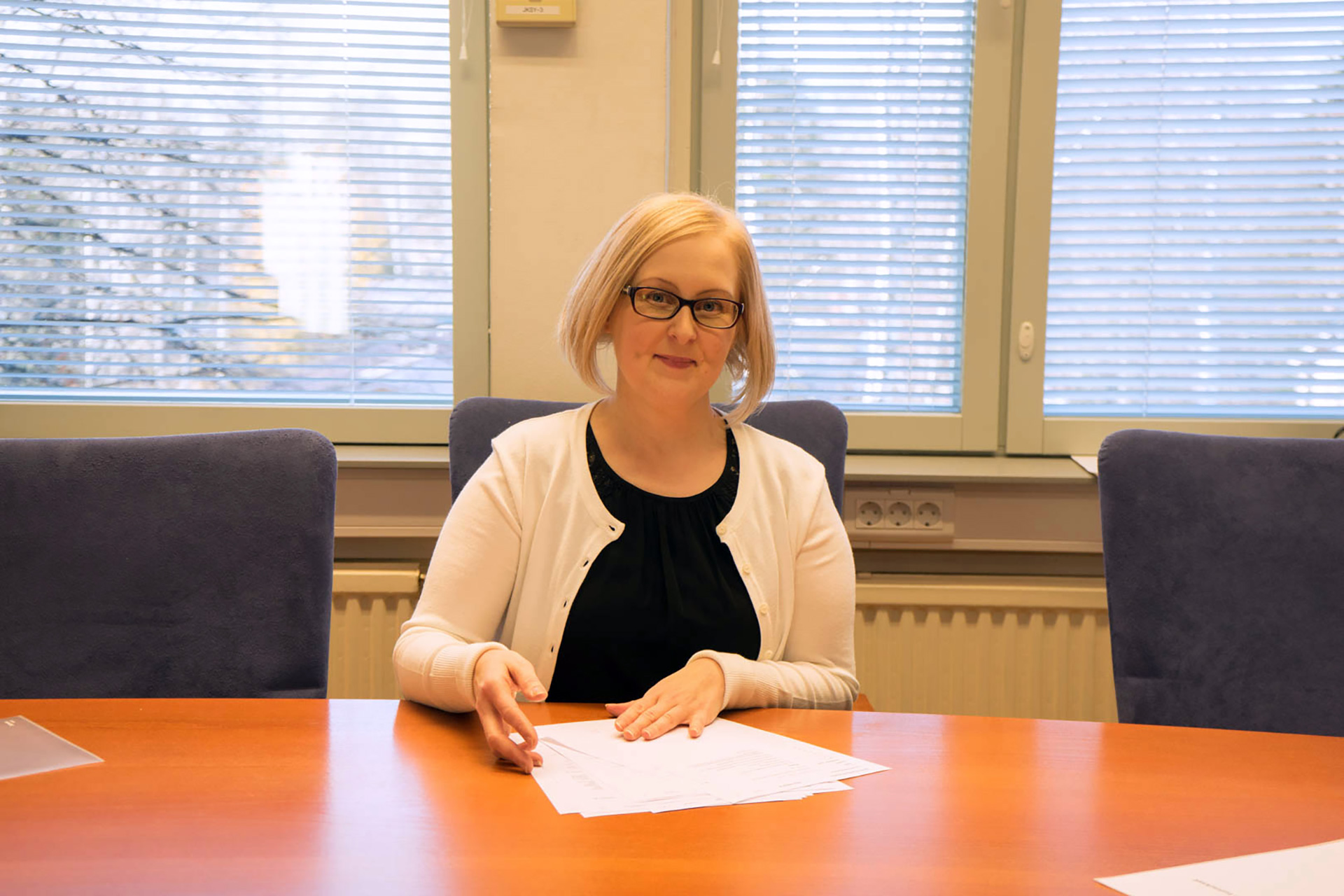 Palvelusihteeri Niina Turunen istuu kunnanhallituksen kokouspöydän ääressä ja käsittelee papereita
